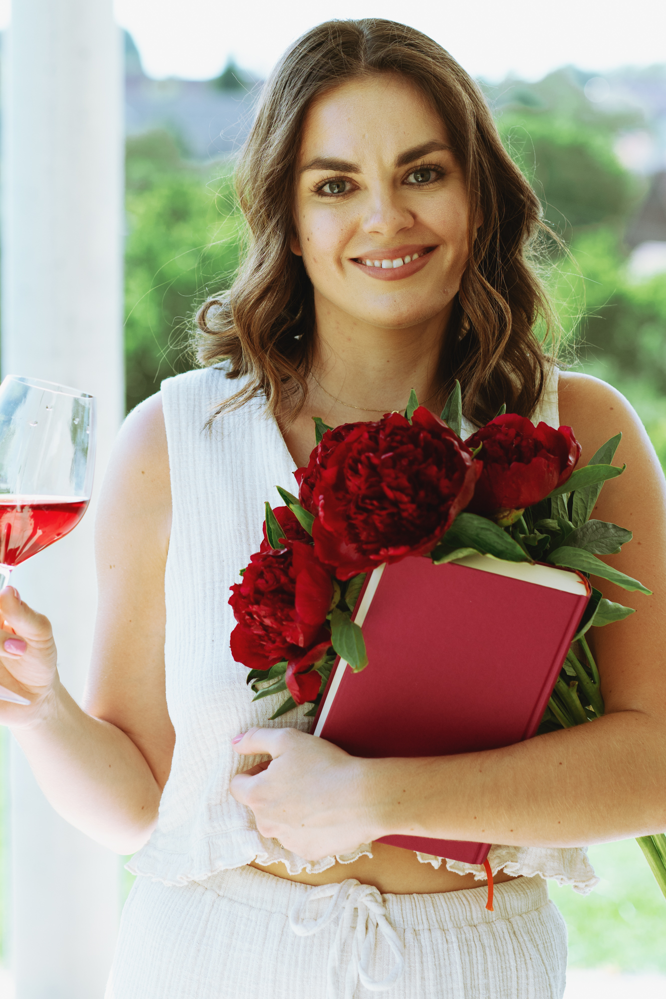 Eine Frau - Unternehmerin mit Buch, Pfingstrosen und Wein